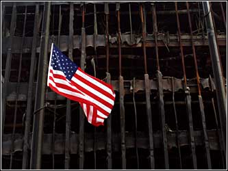 Flag flies in front of building skelton. (cbs)